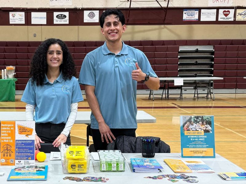 Two people at informational booth in gymnasium.