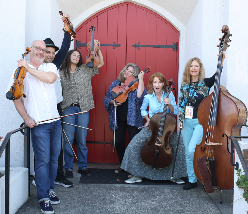 Group of musicians with string instruments posing happily.
