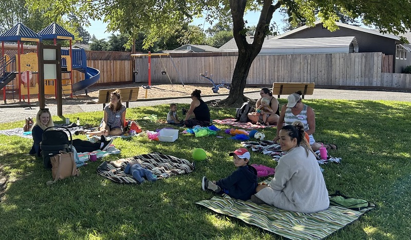 Families having a picnic near playground at park.