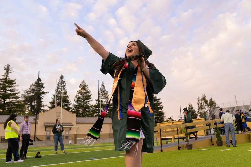 Graduate celebrating on field with cap and gown