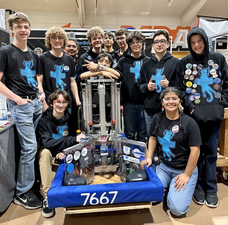 Robotics team posing with their robot at competition.