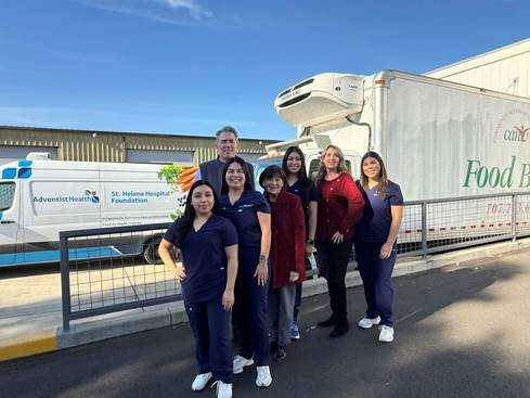 Group posing in front of healthcare and food trucks.