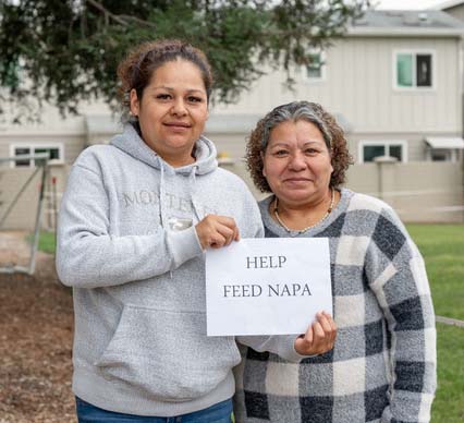 Two people holding 'Help Feed Napa' sign.