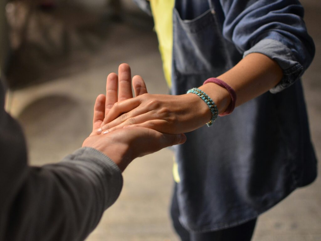 Two people holding hands and offering support.