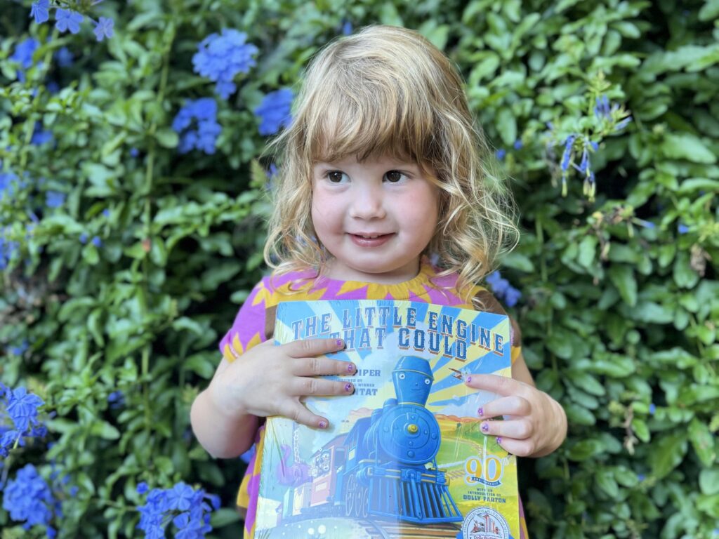 Child holding The Little Engine That Could book.
