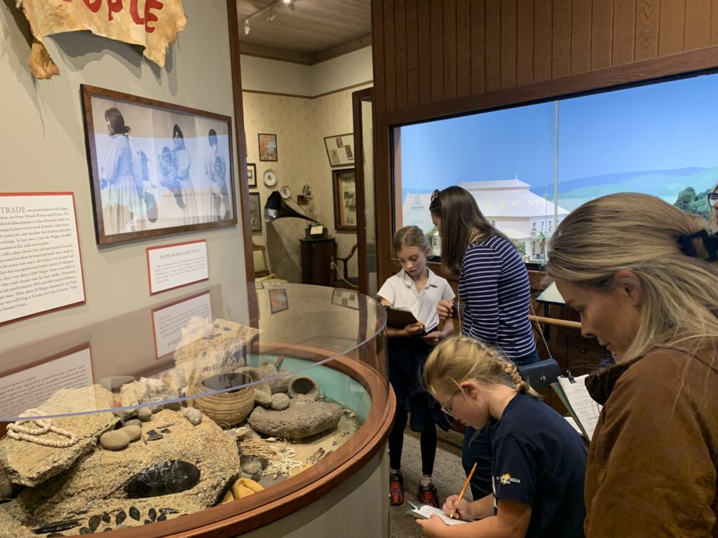 Visitors observing and taking notes in museum exhibit.