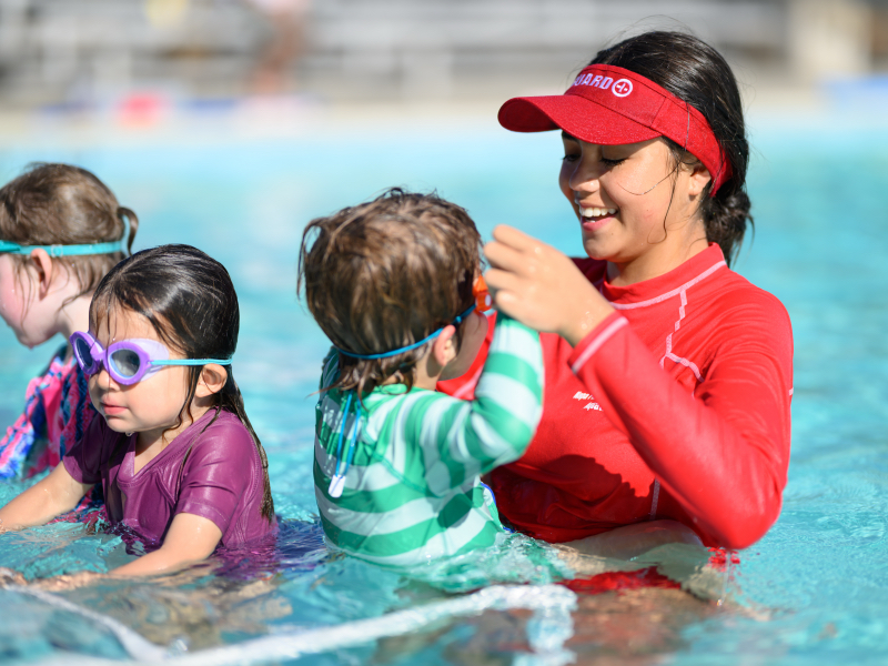 Lifeguard assisting children in swimming pool