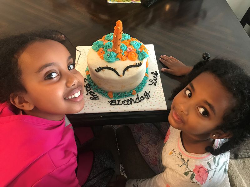Two kids with unicorn birthday cake.